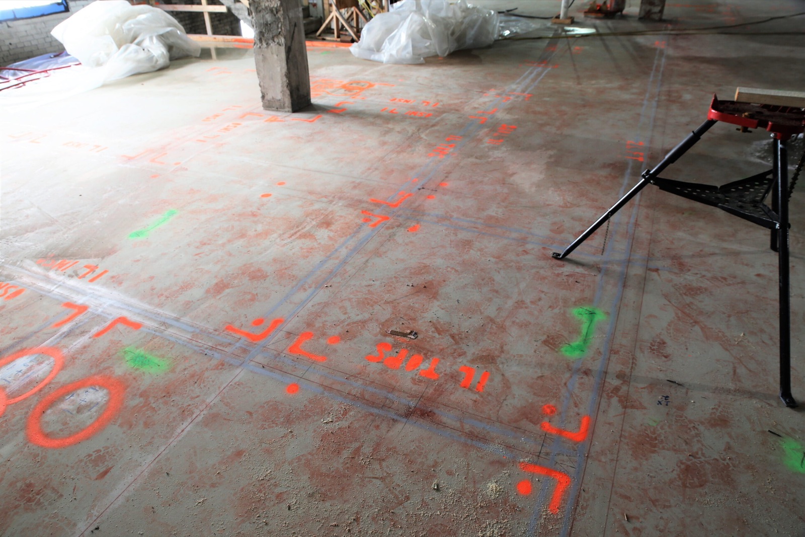 Later multi-trade layout lines and symbols printed on a concrete slab